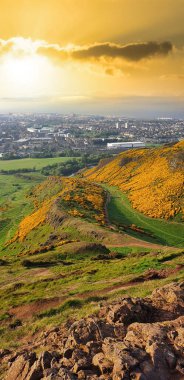 Bir tepeden Edinburgh 'un dikey görüntüsü. Yeşillik, tepeler, binalar, uzaktaki deniz.