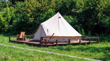 Glamping 'de önünde tahta sandalyeler olan bir çadır. Doğa, yeşillik.