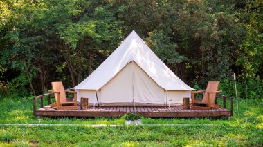 Glamping 'de önünde tahta sandalyeler olan bir çadır. Doğa, yeşillik.