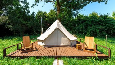 Glamping 'de önünde tahta sandalyeler olan bir çadır. Doğa, yeşillik.