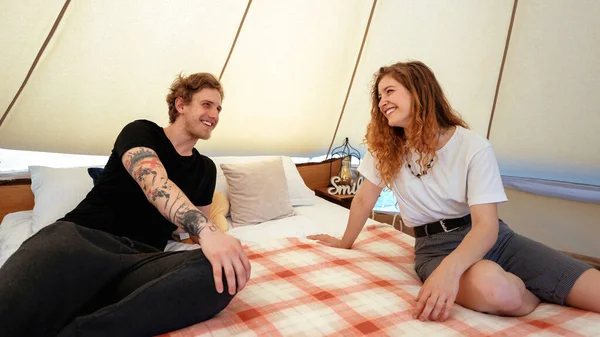 若いカップルは テントの中でベッドの上で魅惑的に休んでいる 笑ったり笑ったり — ストック写真
