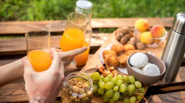 Yemek ve içeceklerle dolu bir masanın üst görüntüsü. Kadın ve erkek alıyor. Glamping