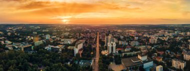 Chisinau şehir merkezindeki hava aracı görüntüsü. Birden fazla bina ve yol manzaralı. Yeşilliklerle dolu bir park. Gün batımı. Moldova