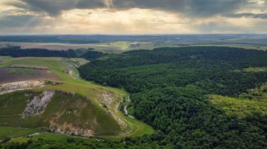 Moldova 'da yüzen dar nehir, tepe yamaçları ve ormanı olan bir vadinin insansız hava aracı görüntüsü