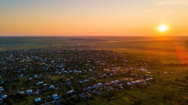 Gün batımında Moldova 'da bir köyün insansız hava aracı görüntüsü. Etrafında geniş alanlar var.