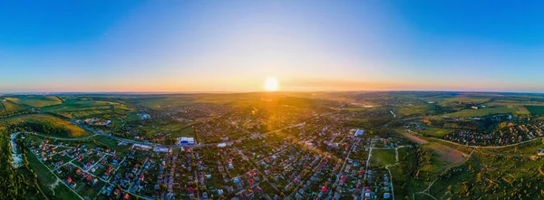 Aerial drone panorama view of Tipova, Moldova at sunset. Roads, residential buildings, fields and hills