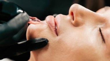 Makyaj ustası müşteri için kalıcı dudak makyajı prosedürünü gerçekleştirir.