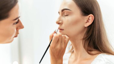 Makyaj ustası bir müşteri için makyaj yapıyor. Dudak boyama