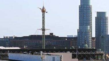 Kopenhag, Danimarka - 6 Ağustos 2025: Tivoli Gardens 'ın ikonik Star Flyer yolculuğunun arka planında modern gökdelenler bulunan insansız hava aracı görüntüsü