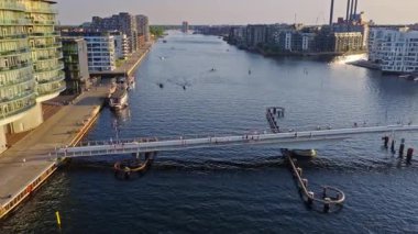 Lille Langebro yaya köprüsünün hava aracı görüntüsü. İnsanlar Kopenhag, Danimarka 'da gün batımında limanda bisiklet sürüyor ve yürüyor.