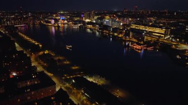 Danimarka 'daki modern binaların renkli ışıklarının yansımalarıyla Kopenhag Limanı' nın gece hava aracı görüntüsü