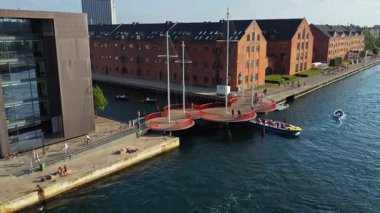 Kopenhag, Danimarka - 7 Ağustos 2025: Kopenhag 'daki Christianshavn Kanalı üzerindeki Çember Köprüsü' nün bisikletçiler ve botlarla hava aracı görüntüsü
