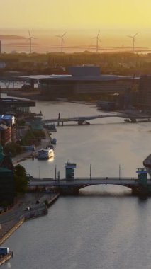 Güneş doğarken Kopenhag 'ın kanallarını ve köprülerini gösteren hava aracı görüntüsü, şehri ve limanı aydınlatan altın ışıkla birlikte. Dikey