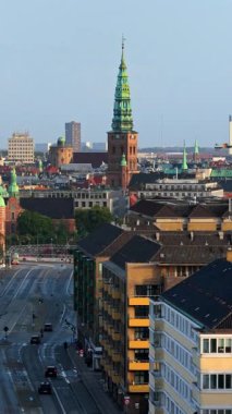 Kopenhag 'ın merkezinde, güneş doğarken St. Nicholas Kilisesi' nin kulesiyle hava aracı görüntüsü. Dikey