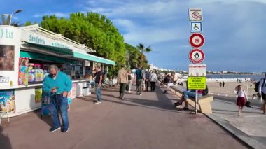 Cannes, Fransa - 20 Eylül 2025: Güneşli cadde kafeler, restoranlar ve butik dükkanlarıyla dolu, insanlar Riviera atmosferinde geziniyor ve eğleniyor