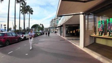 Cannes, Fransa - 20 Eylül 2025: Lüks butikleri olan şık bir cadde, Croisette boyunca palmiye ağaçları ve arka planda Akdeniz manzarası