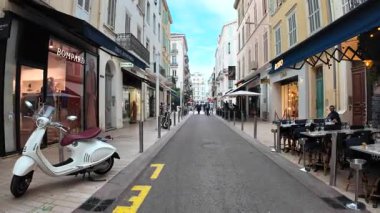 Cannes, Fransa - 20 Eylül 2025: Açık hava restoranları, butik dükkanları ve Vespas park halindeki Akdeniz atmosferini yakalayan büyüleyici dar sokaklar