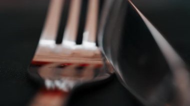 Lokantadaki siyah bir peçeteye yerleştirilmiş gümüş çatal bıçak takımını kapat.