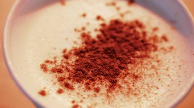 Köpüklü sütün üzerine serpiştirilmiş kakao, bol ılık tonlarda.