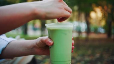 Açık havada elinde buzlu kibritli latte tutan bir kadının elini yakın plan.