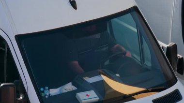 Chisinau, Moldova - 28 Eylül 2025: Beyaz bir minibüsün direksiyonunda oturan bir adam, ön camdan bakıldı