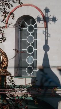 Güzel bir mimari detay dairesel pencereli bir duvara yansıtılan kilise haçının gölgesini gösteriyor. Dikey