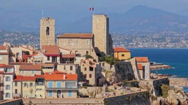 Antibes Eski Kasabası 'ndaki Picasso Müzesi' nin hava aracı görüntüsü. Ortaçağ taş kuleleri, Fransız bayrağı dalgalanması ve deniz manzaralı terasotta çatıları.