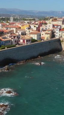 Antibes Eski Kasabası 'nın terasotta çatıları, palmiye ağaçları ve Akdeniz' e bakan ortaçağ tahkimatları olan insansız hava aracı görüntüsü. Dikey