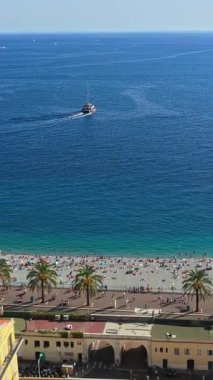 Nice sahilinin ve Anglais 'in hava aracı görüntüsü. Palmiye ağaçları, turkuaz deniz ve açık denizde yelkenli bir tekne. Dikey