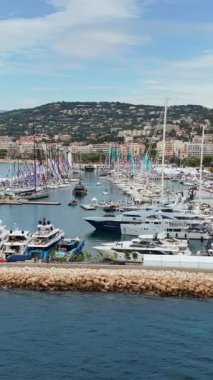 Arka planda lüks yatlar, yelkenliler ve deniz manzaralı otellerle dolu Cannes limanının insansız hava aracı görüntüsü. Dikey