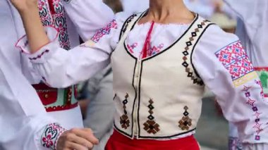 Canlı geleneksel kıyafetler içindeki dansçılar, yerel gelenek ve kültürü neşeli ifadelerle kutlayarak, bir halk meydanındaki bir yaz festivalinde canlı halk dansları yapıyorlar. Yavaş çekim