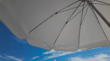 Beyaz plaj şemsiyeleriyle güneşli deniz manzarası Parlak mavi bir gökyüzü ve sakin bir deniz çerçevesi