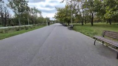 Sonbahar ağaçları ve banklarla dolu bir parkta bisiklet sürerken çekilmiş bir bakış açısı