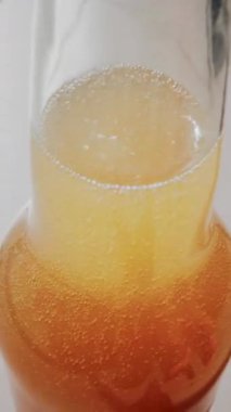 Bardağın içinde köpüklü altın kabarcıklar olan köpüklü içeceğin yakın görüntüsü. Dikey