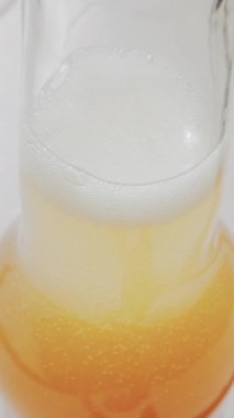 Bardağın içinde köpüklü altın kabarcıklar olan köpüklü içeceğin yakın görüntüsü. Dikey