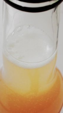 Bardağın içinde köpüklü altın kabarcıklar olan köpüklü içeceğin yakın görüntüsü. Dikey