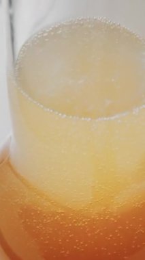 Bardağın içinde köpüklü altın kabarcıklar olan köpüklü içeceğin yakın görüntüsü. Dikey