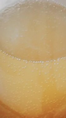 Bardağın içinde köpüklü altın kabarcıklar olan köpüklü içeceğin yakın görüntüsü. Dikey