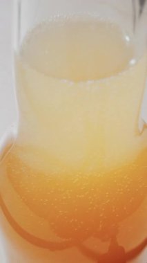 Bardağın içinde köpüklü altın kabarcıklar olan köpüklü içeceğin yakın görüntüsü. Dikey