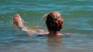 Cannes, Fransa 'da sakin mavi denizde gün ışığında yüzen bir kadın.