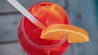 Serinletici bir Aperol Spritz kokteylini portakal dilimi ve buzla kapatıyoruz. Güneşli bir günde Cannes 'da açık havada çekiyoruz.