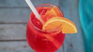 Serinletici bir Aperol Spritz kokteylini portakal dilimi ve buzla kapatıyoruz. Güneşli bir günde Cannes 'da açık havada çekiyoruz.