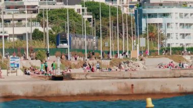 Cannes, Fransa - 6 Ekim 2025: İnsanlar yürürken ve yakınlarda dinlenirken modern bir tren sahilin kıyısından geçiyor