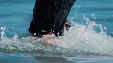 Cannes, Fransa - 8 Ekim 2025: Açık mavi denize dalıp bacaklarının etrafına su sıçratan bir çocuğa yakın durun.