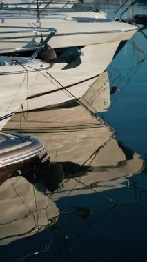 Yat, halat ve bir marinanın parlak yüzeyindeki çapaların çarpık yansımaları. Dikey