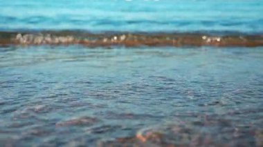 Sabah ışığı altında kumlu sahilde yavaşça akan küçük dalgaları kapat.