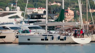 Cannes, Fransa - 9 Ekim 2025: Yelkenliler ve yatlar, insanların güvertede hazırlandığı bir marinaya kenetlenmiştir.