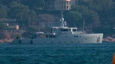 Sakin mavi sularda yüzen parlak sarı bir şamandıra ve arka planda bulanık bir yat.