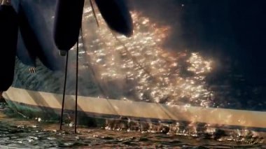 Güneş ışığı lüks bir yatın parlak tarafında dans eder, ılık altın tonlarını yansıtır nazik dalgalar boyunca.