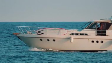 Modern beyaz bir yat, berrak gökyüzünün altında mavi denizde sorunsuzca yol alır.